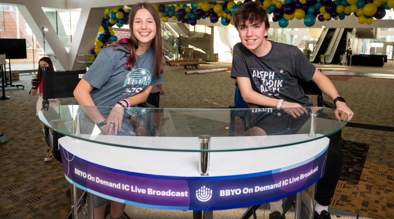 A diverse crowd of people celebrating at a concert, raising their hands and cheering.